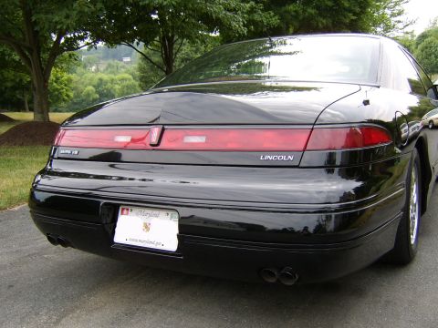 1996 Mercury Grand Marquis - The rear of a black Lincoln Mark VIII is shown, its distinctive taillight bar and dual exhaust pipes.