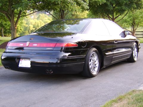 1996 Mercury Grand Marquis - Rear view of a black Lincoln Mark VIII coupe parked on a paved surface with trees in the background.