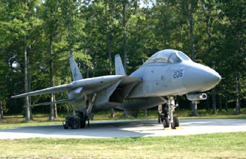 1972 Ford Ranchero - A U.S. Navy F-14 Tomcat fighter jet is displayed outdoors, parked on a concrete pad with a backdrop of trees.