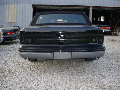 1972 Ford Ranchero - Rear view of a black car with a black vinyl top, missing taillights, and a grey bumper.