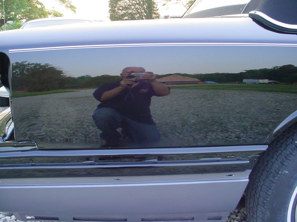 guy taking photo reflected in side of dark car