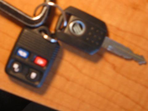 2002 Mercury Sable - A set of car keys, one fob displaying the Mercury logo, lies on a wood-grain surface.