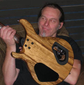 1972 Ford Ranchero - Man holding back of a wooden electric bass guitar with visible electronics compartment.