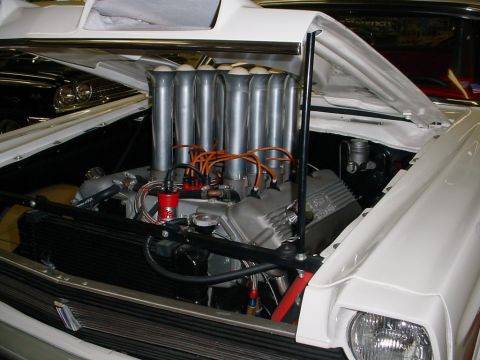 1972 Ford Ranchero - The engine bay of a white 1972 Ford Ranchero, chrome stacks and a prominent hood scoop.