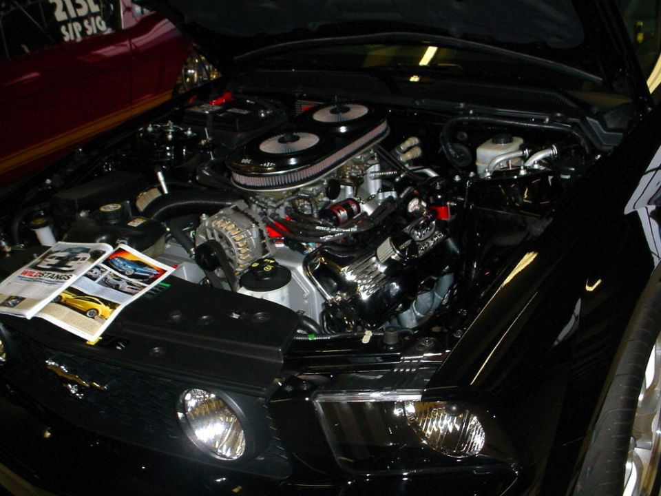 Black car engine bay with chrome air intake and magazines on the fender