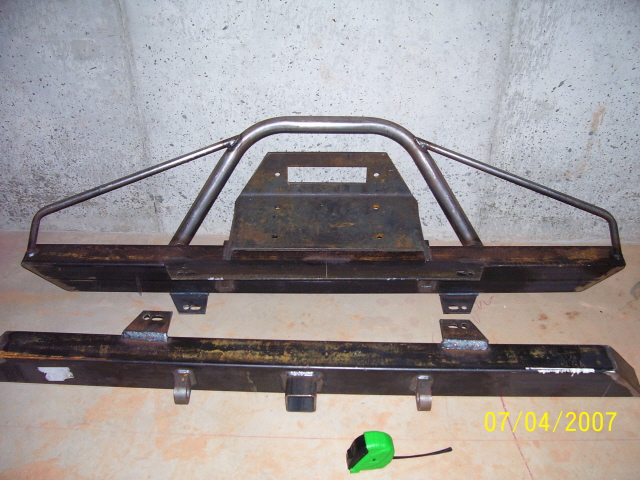Two metal bumpers, one with a roll cage-like hoop, sit on the floor