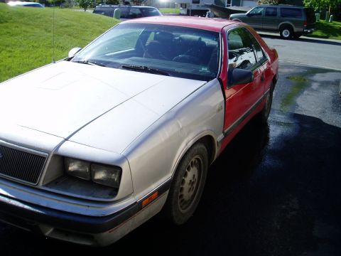 2000 Ford E350 - This Chrysler LeBaron coupe has a silver front end and red doors, parked outside.