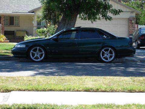 1993 Ford Taurus - A dark green 1993 Ford Taurus sedan is parked on a residential street.