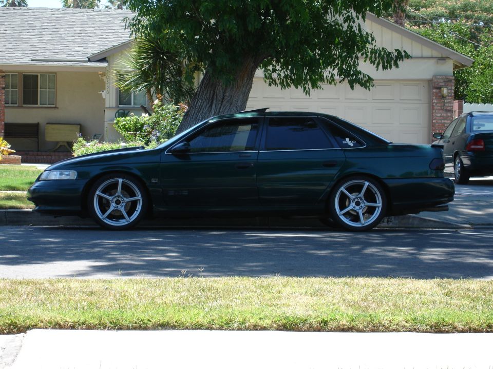 Dark green 1993 Ford Taurus sedan side view with aftermarket wheels