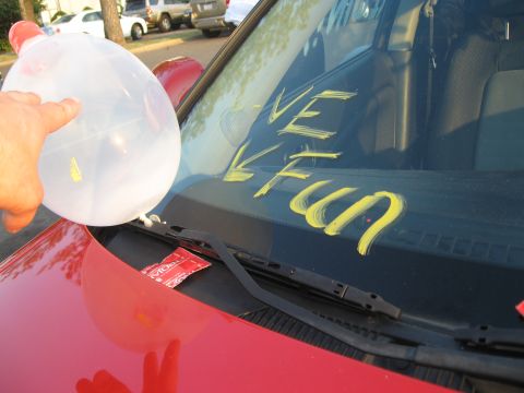 1988 Ford Bronco - A car windshield has yellow writing and a hand holding a balloon.