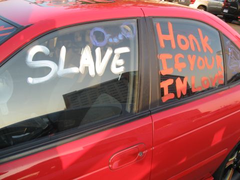 1988 Ford Bronco - A red car has messages written on its windows, including 'SLAVE' and 'Honk IF YOUR IN LOVE'.