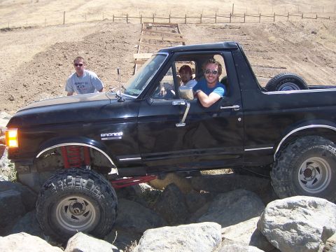 1991 Ford Bronco - This black Ford Bronco is equipped with a lifted suspension and is navigating a rocky terrain.