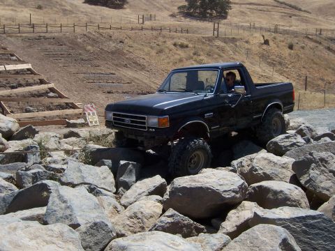 1991 Ford Bronco - This black Ford Bronco is navigating a rocky terrain, its off-road capabilities.