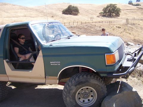1991 Ford Bronco - A modified green 1991 Ford Bronco is shown off-road, large tires and a custom front bumper.