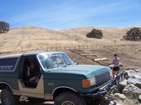 1991 Ford Bronco - A modified Ford Bronco is parked on a rocky trail with a woman standing in the background.