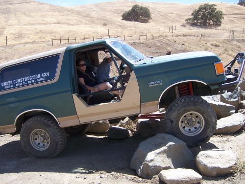 1991 Ford Bronco - A Ford Bronco navigates a rocky off-road course with two people inside.