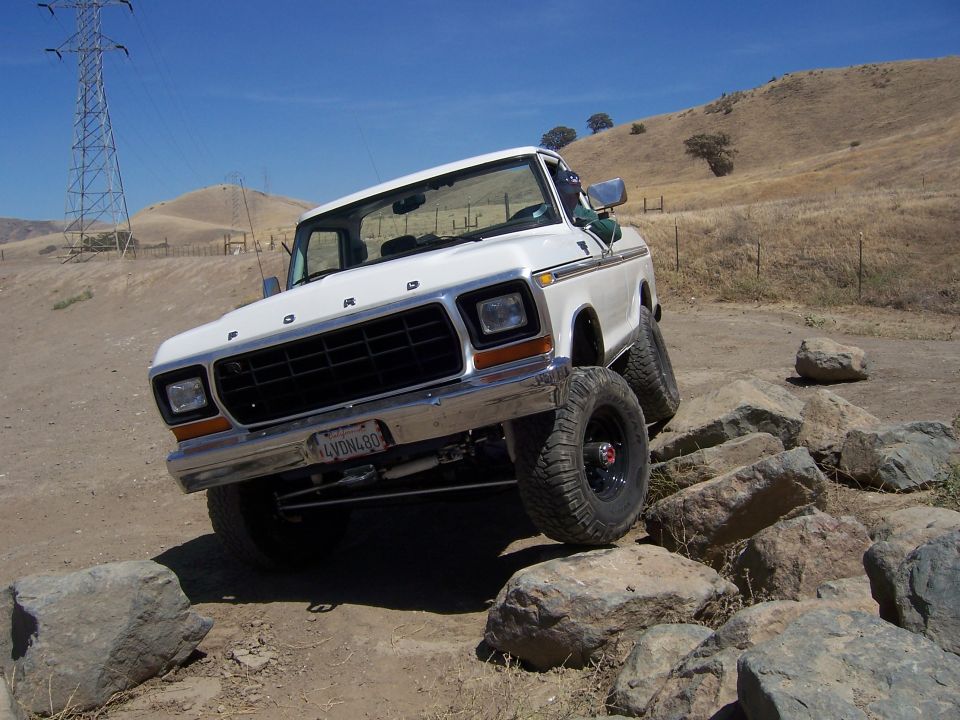 White Ford F-Series truck on rocks. License plate reads 4VDNL80