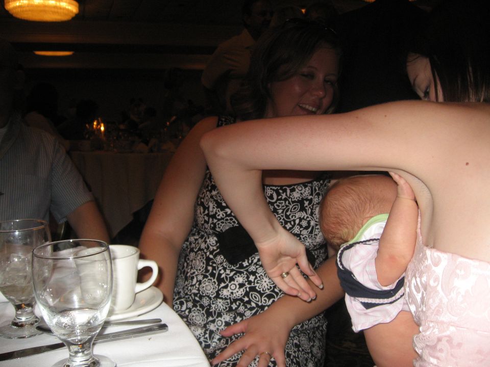 People gathered around a table with drinks and a baby