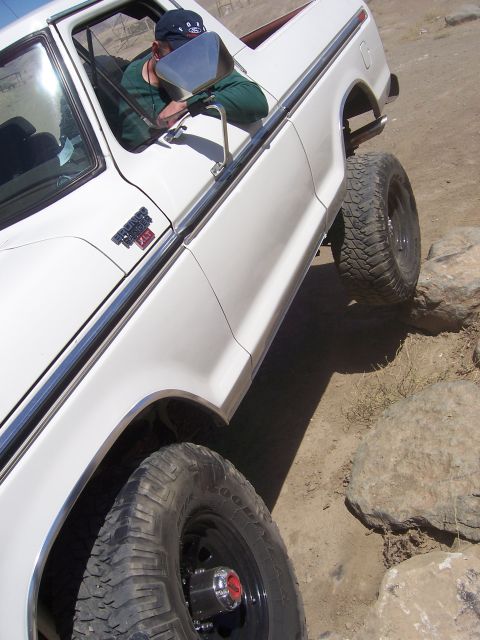 1991 Ford Bronco - White Ford Bronco with off-road tires navigating rocky terrain.