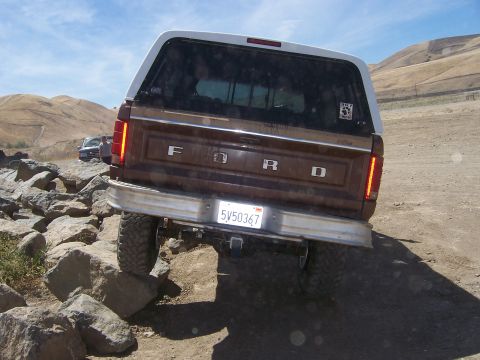 1991 Ford Bronco - This Ford Bronco, likely from the 1980s, navigates a rocky trail with a white camper shell.