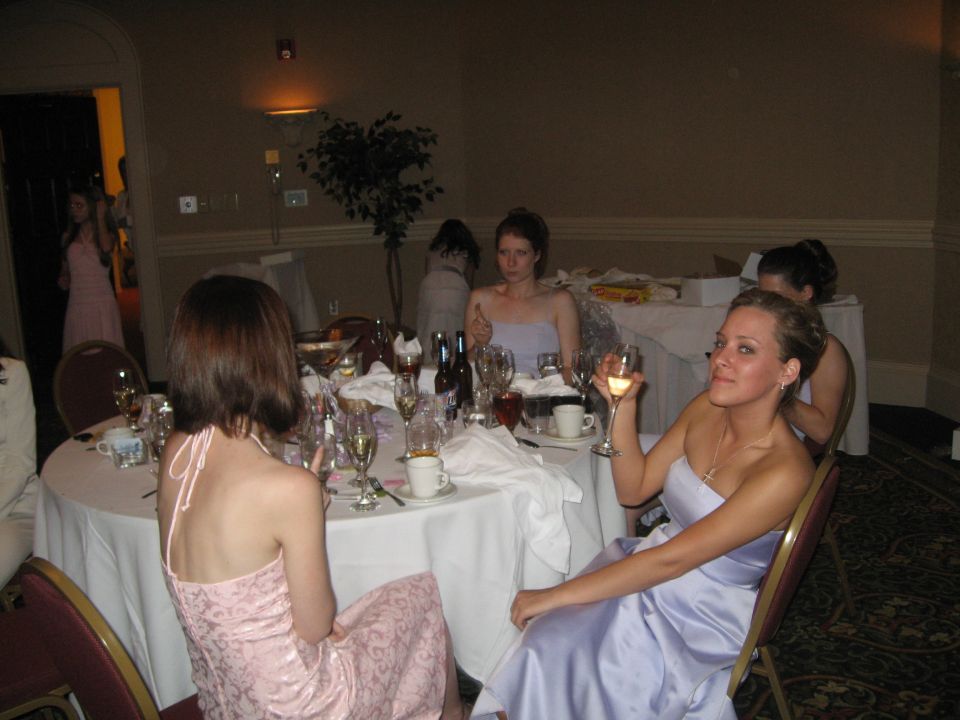 Wedding reception with guests seated at round tables, some holding wine glasses