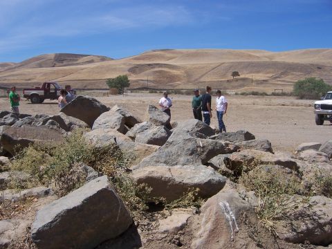 1991 Ford Bronco - People gather near vehicles in a rocky, arid landscape under a clear blue sky.