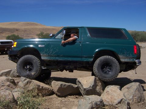 1991 Ford Bronco - A 1991 Ford Bronco navigates a rocky trail under a clear blue sky.