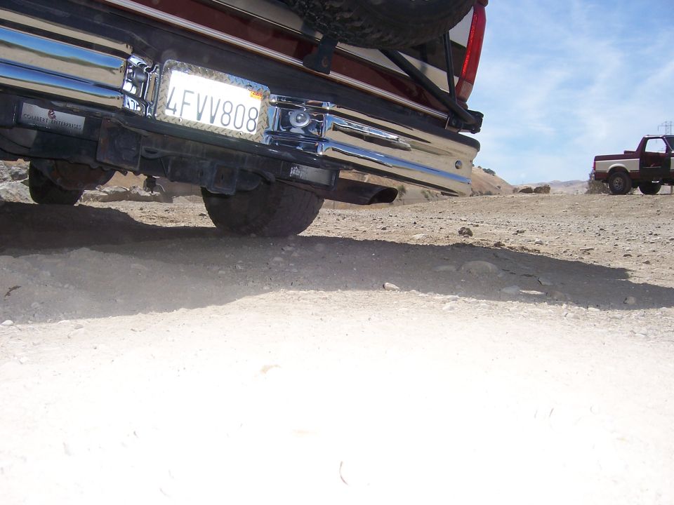 Rear view of a 1991 Ford Bronco on a dirt road with another truck in the distance
