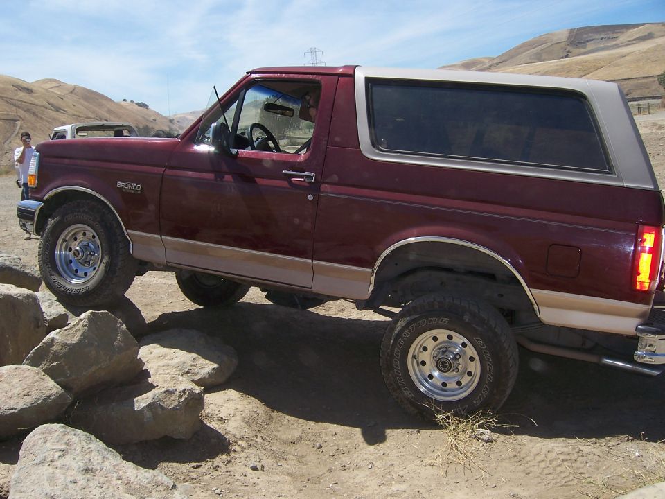 Maroon 1991 Ford Bronco 3q-front view driving over rocks