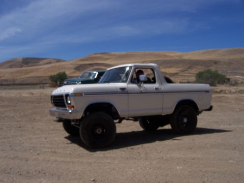 1991 Ford Bronco - White 1978 Ford Bronco with lifted suspension and off-road tires sits in a dry, hilly landscape.