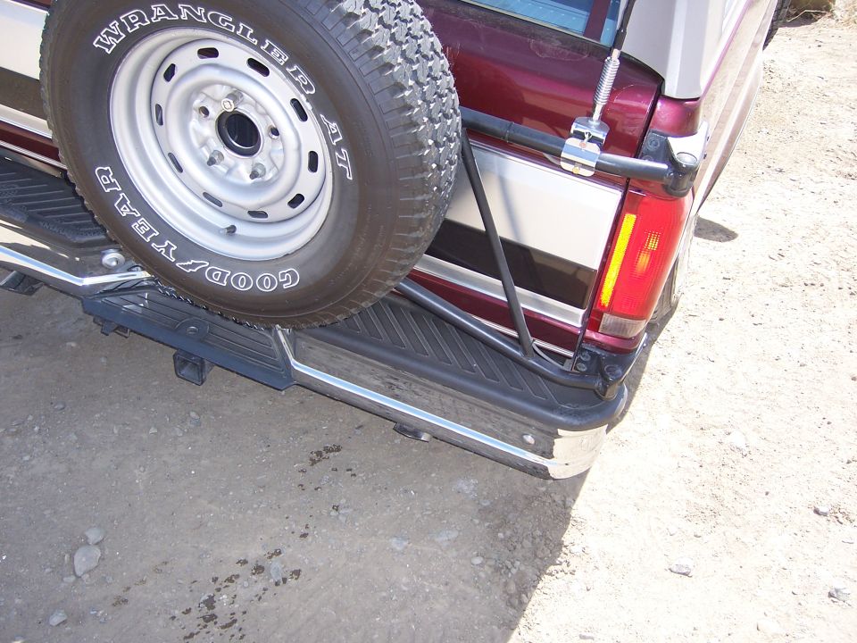 Maroon and silver SUV rear with spare tire. 1991 Ford Bronco