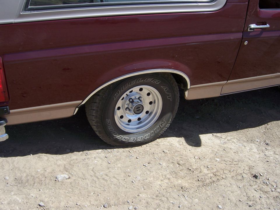 1991 Ford Bronco rear wheel with Dunlop A/T tire and chrome trim on fender