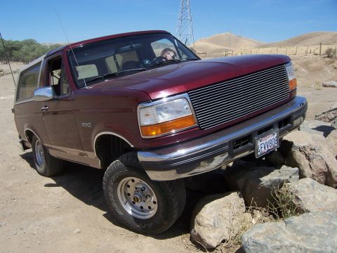 1991 Ford Bronco - A Ford Bronco navigates a rocky trail under a clear blue sky.
