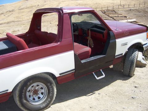 1991 Ford Bronco - This two-tone red and white 1991 Ford Bronco is seen with its doors removed, revealing the interior and rear seating area.