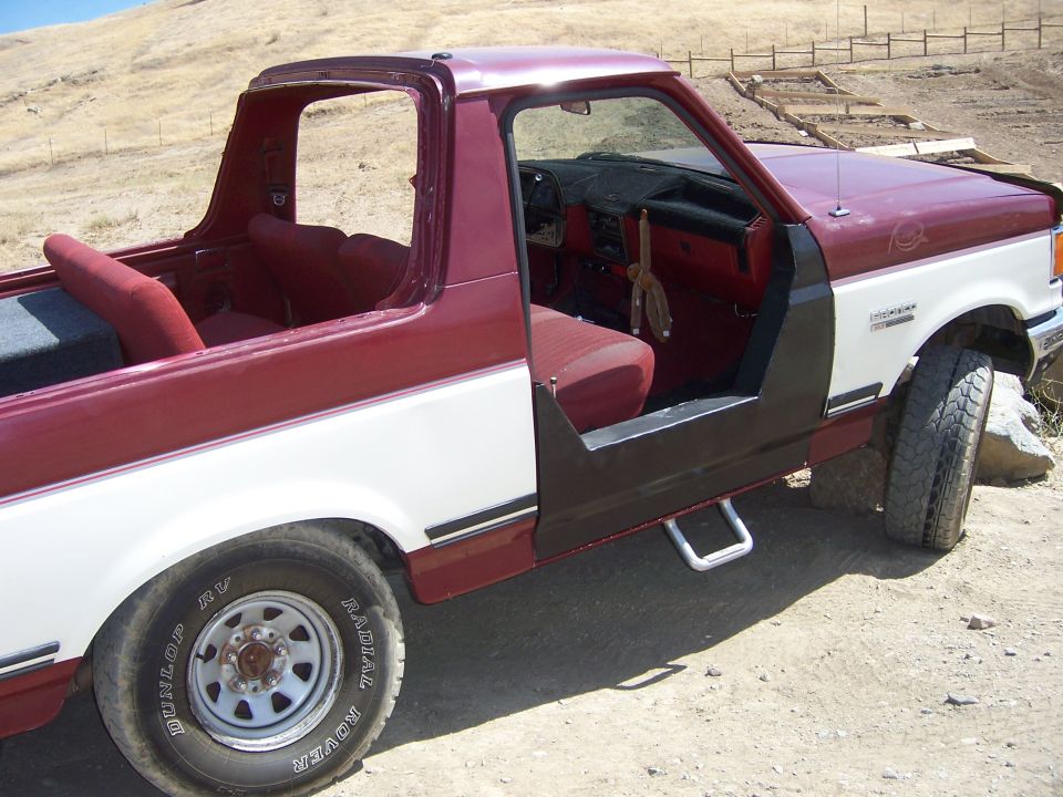 Red and white 1991 Ford Bronco with doors removed, interior visible