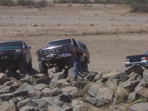1991 Ford Bronco - Multiple SUVs, including a maroon Ford Bronco, traverse a challenging rocky landscape.