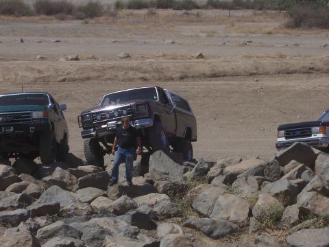 1991 Ford Bronco - Several modified trucks are shown traversing a challenging rocky terrain.
