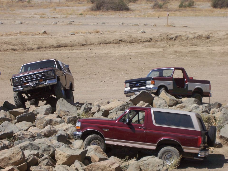 Three off-road vehicles, two Ford Broncos and one Ford F-150, navigating a rocky terrain