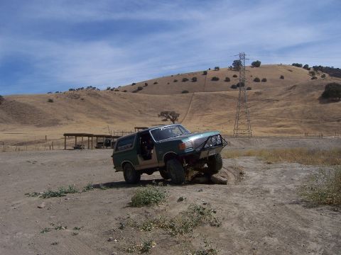 1991 Ford Bronco - 1991 Ford Bronco tackling an off-road trail with a hill and power lines in the background.