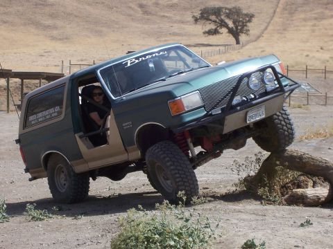 1991 Ford Bronco - A modified Ford Bronco navigates an obstacle on a dirt trail, its off-road capabilities.