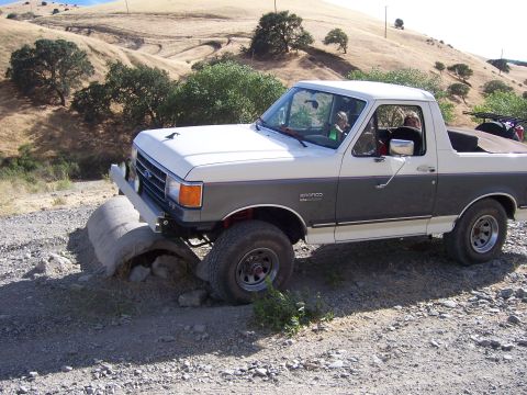 1991 Ford Bronco - This 1991 Ford Bronco navigates a challenging off-road obstacle on a dirt path.