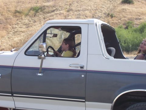 1991 Ford Bronco - A young girl smiles while driving a two-tone white and grey Ford Bronco on a sunny day.