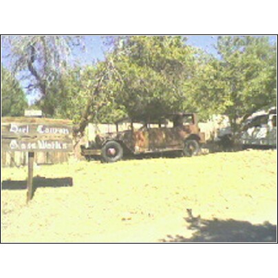 1973 Ford Ranchero - An old, weathered car sits in a yard next to a wooden sign, with another vehicle in the background.