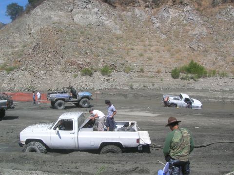 1985 Ford Bronco - Off-road vehicles struggle to navigate through a muddy terrain, with some becoming deeply stuck.