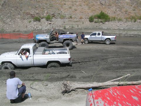 1985 Ford Bronco - Multiple trucks are stuck in the mud during a recreational off-roading event.