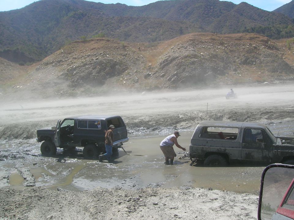 Two SUVs stuck in mud, one being pulled by the other