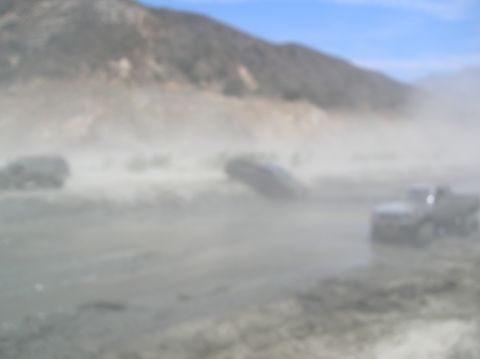 1985 Ford Bronco - Multiple vehicles are visible in a dusty, outdoor environment with hills in the background.