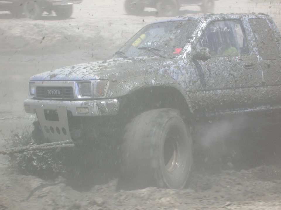 Mud-covered Toyota truck in a mud bog, front 3/4 view