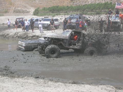 1985 Ford Bronco - Several vehicles are stuck in the mud during an off-road event.