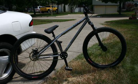 1997 Ford Probe - A dirt jump bicycle is parked next to a white car on a residential street.